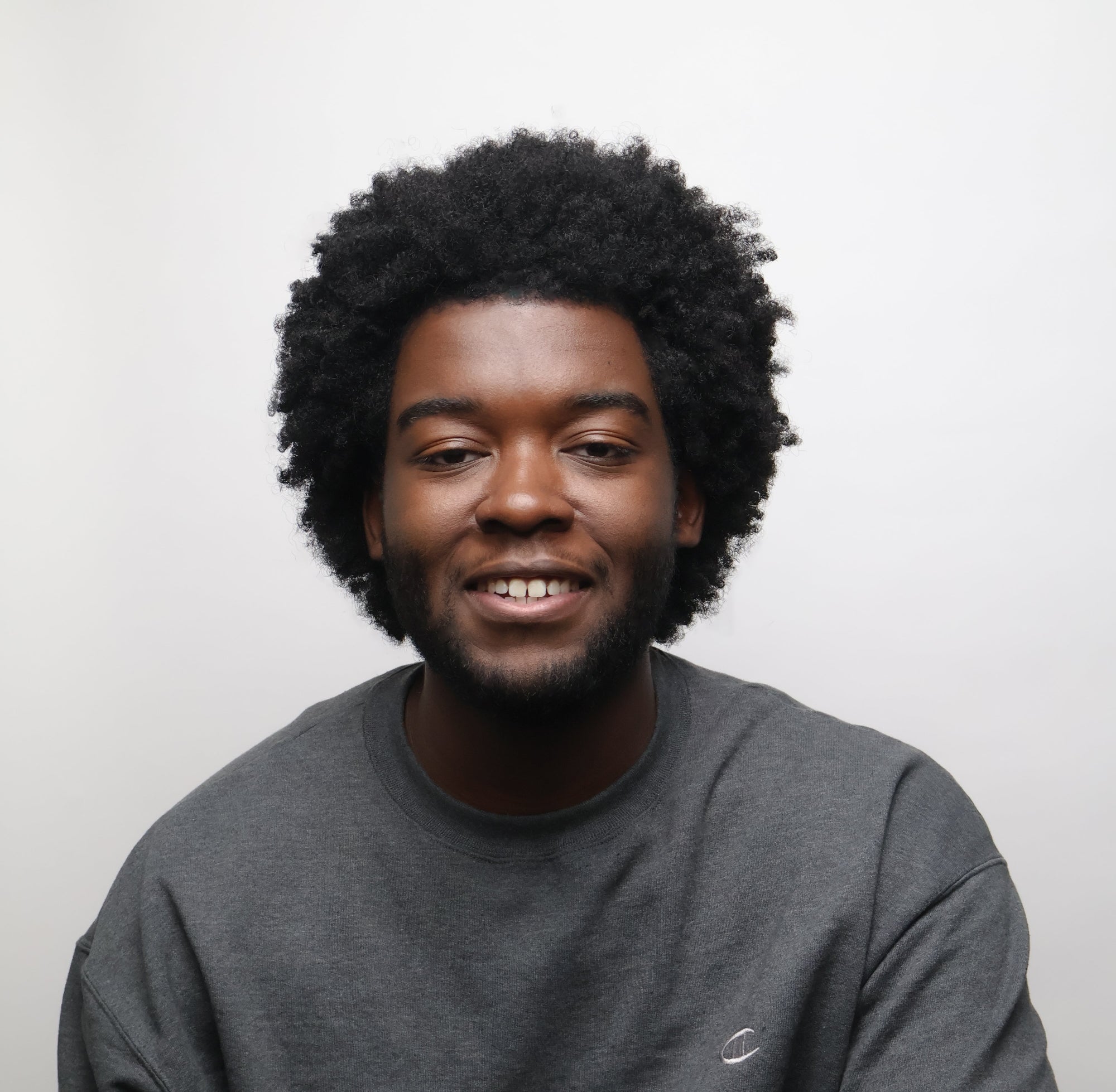 Man with afro sitting and smiling
